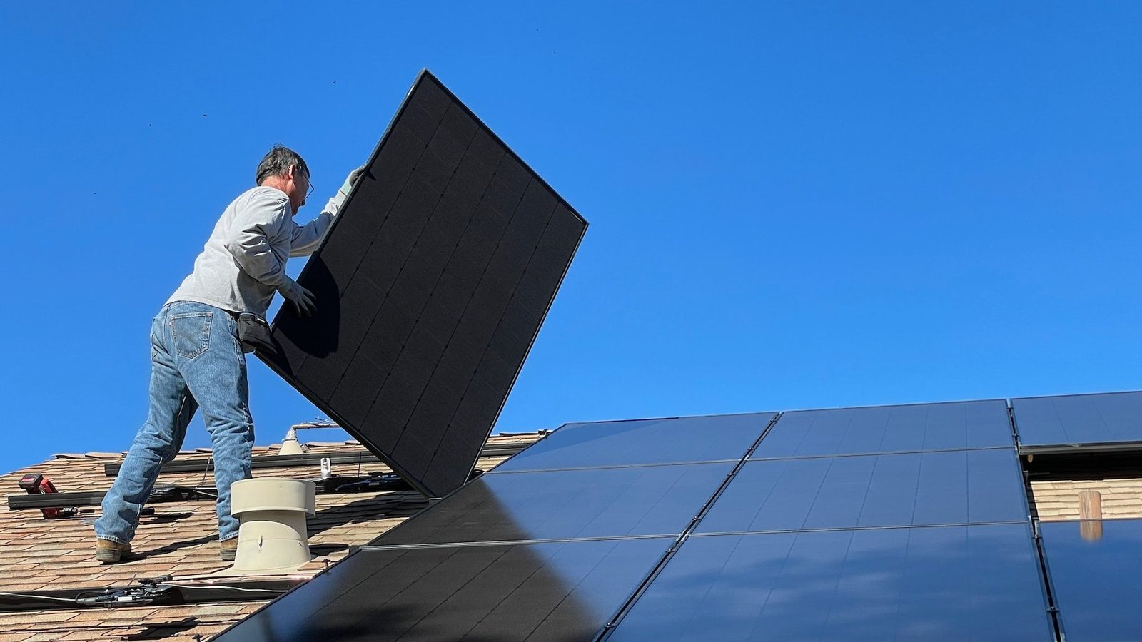 Man on roof installing solar panels on a sunny day